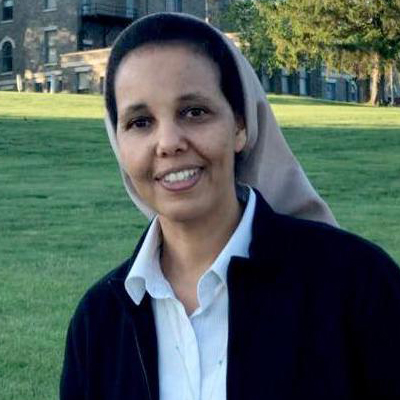 A nun wearing a tan habit smiling