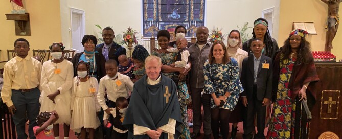 Group of children and adults standing in front of the church altar with the parish priest